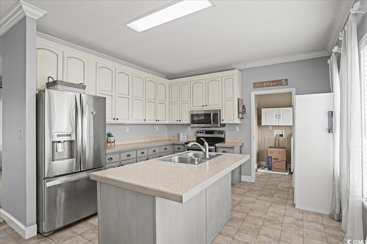 706 Beverly Hills Road Camden, SC 29020 - Photo 7 of 25 Kitchen with light countertops, appliances with stainless steel finishes, a center island with sink, crown molding, and a textured ceiling