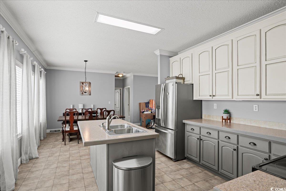 706 Beverly Hills Road Camden, SC 29020 - Photo 10 of 25 Kitchen with ornamental molding, decorative light fixtures, light countertops, stainless steel fridge with ice dispenser, and an island with sink