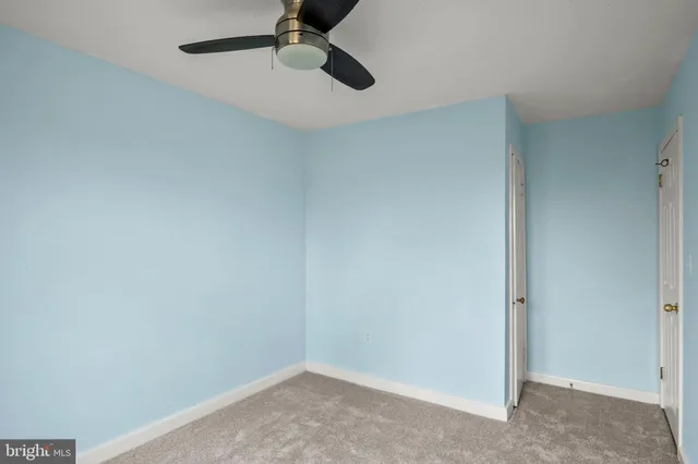 an empty room with a ceiling fan and carpet