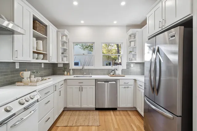 a kitchen with stainless steel appliances granite countertop a refrigerator sink and white cabinets