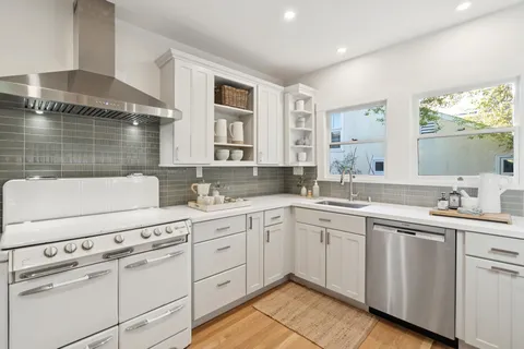 a kitchen with white cabinets and sink
