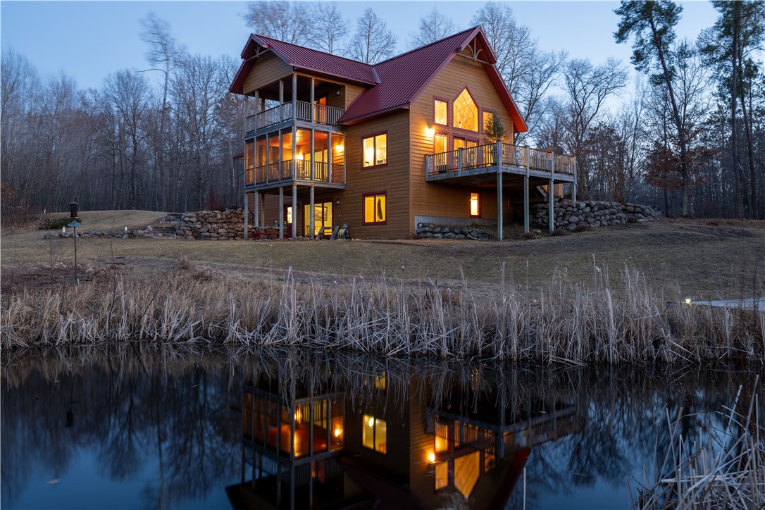 1257-1261 Lipsett Access Road Spooner, WI 54801 - Photo 1 of 1 This beautiful twilight photo highlights the many windows in this home.