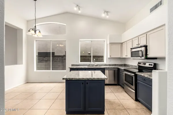 a large kitchen with granite countertop a stove sink and cabinets