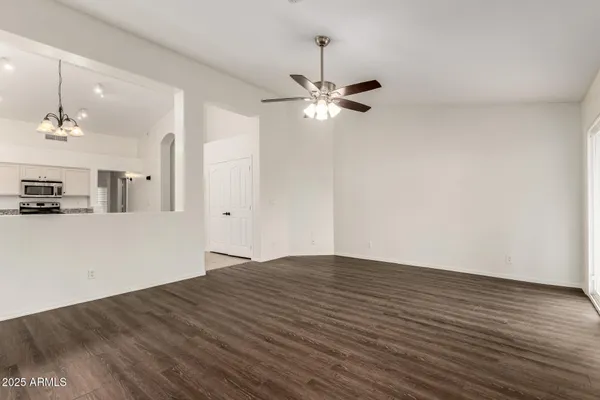 a view of empty room with wooden floor and ceiling fan