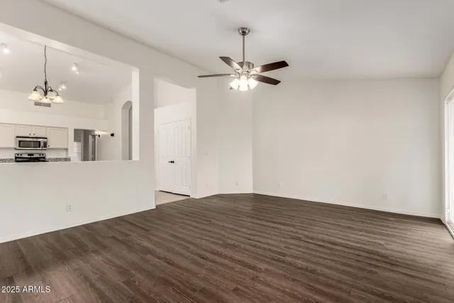 a view of empty room with wooden floor and ceiling fan