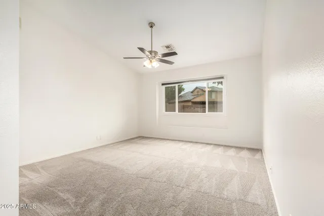an empty room with a window and a ceiling fan