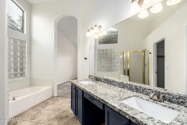 a bathroom with a granite countertop bathtub a sink and a mirror