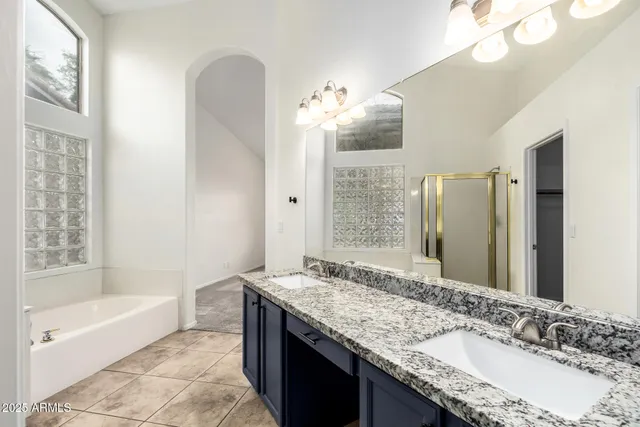 a bathroom with a granite countertop bathtub a sink and a mirror