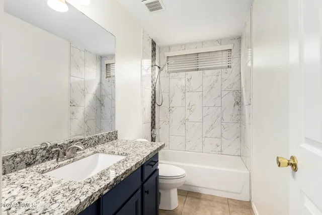 a bathroom with a granite countertop sink a toilet and shower