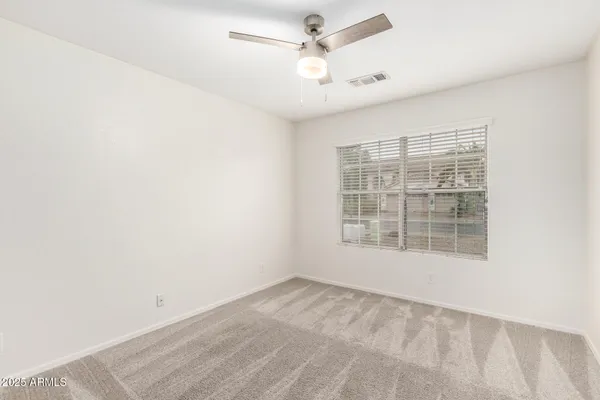 an empty room with a window and ceiling fan