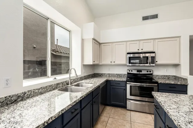 a kitchen with granite countertop stainless steel appliances a stove sink and cabinets