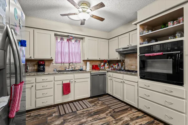 a kitchen with stainless steel appliances kitchen island granite countertop a sink and cabinets