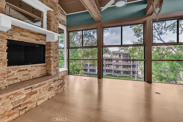 a view of an empty room with wooden floor and a fireplace