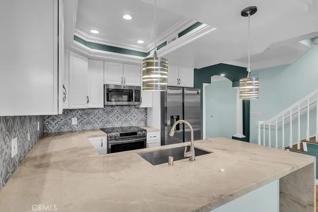 a kitchen with stainless steel appliances kitchen island granite countertop a refrigerator a stove a sink and a microwave