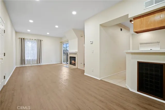 a view of empty room with wooden floor and fireplace