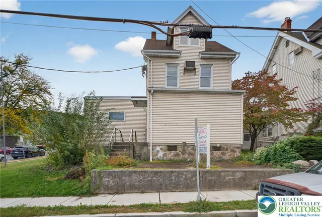 a view of a white house with large windows and a yard