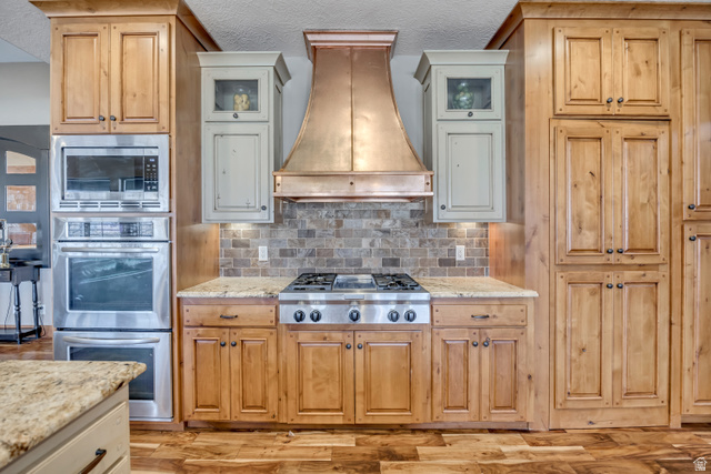 896 West 675 South Mapleton, UT 84664 - Photo 9 of 77 Kitchen featuring appliances with stainless steel finishes, a textured ceiling, custom range hood, and light stone counters