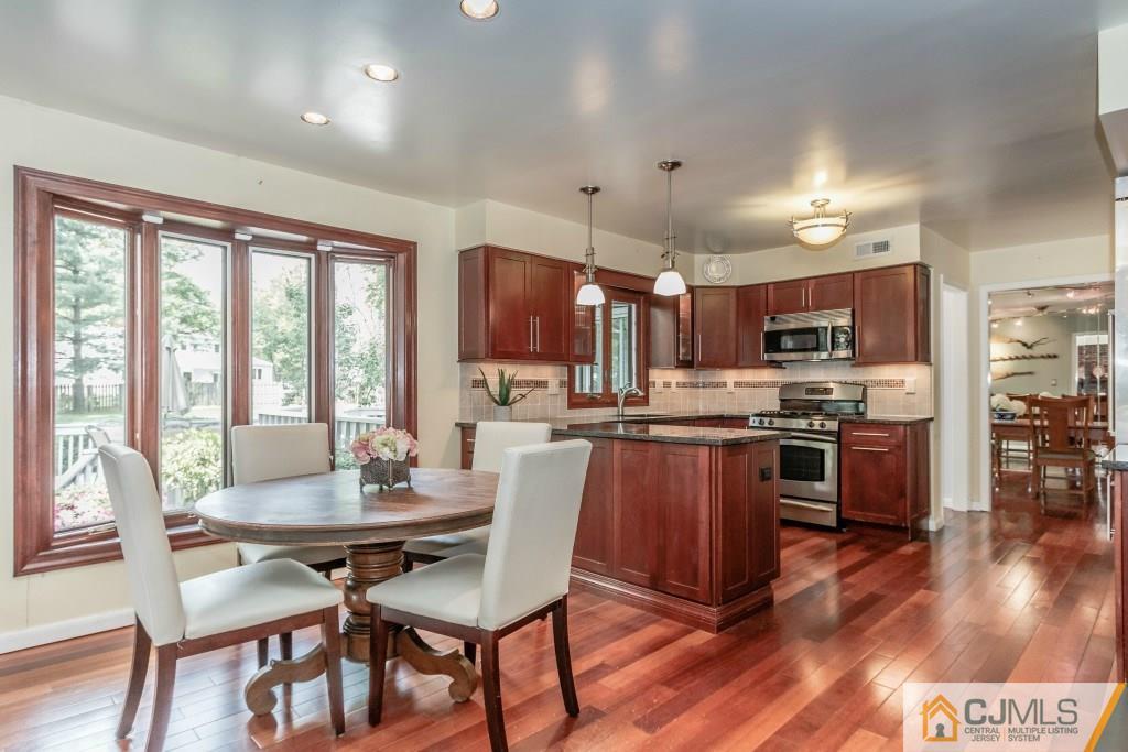 26 Fox Hill Road Edison, NJ 08820 - Photo 7 of 23 a kitchen with stainless steel appliances kitchen island granite countertop a stove a refrigerator a kitchen island a dining table and chairs