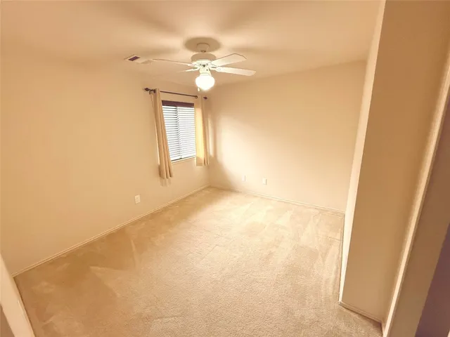 a view of an empty room and chandelier fan