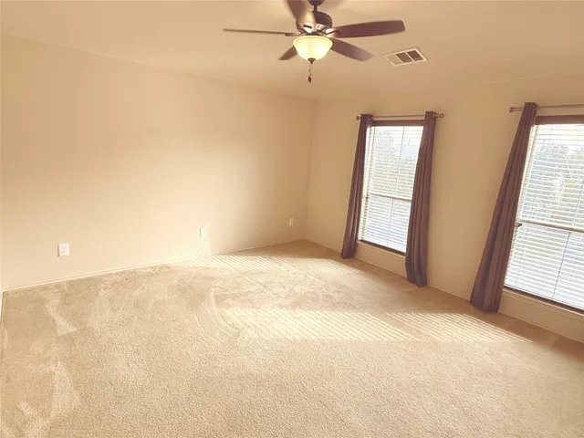 an empty room with windows and fan
