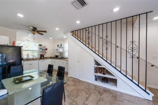 a kitchen with stainless steel appliances granite countertop a refrigerator a sink dishwasher a dining table and chairs with wooden floor