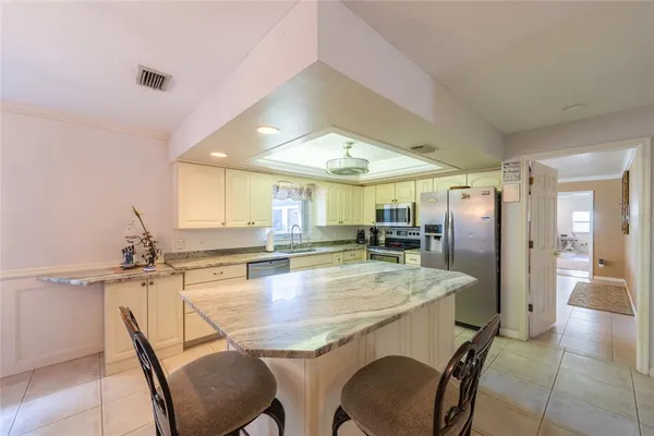 a dining hall with stainless steel appliances granite countertop a dining table and chairs