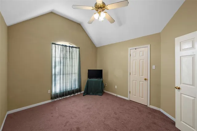an empty room with chandelier fan and windows