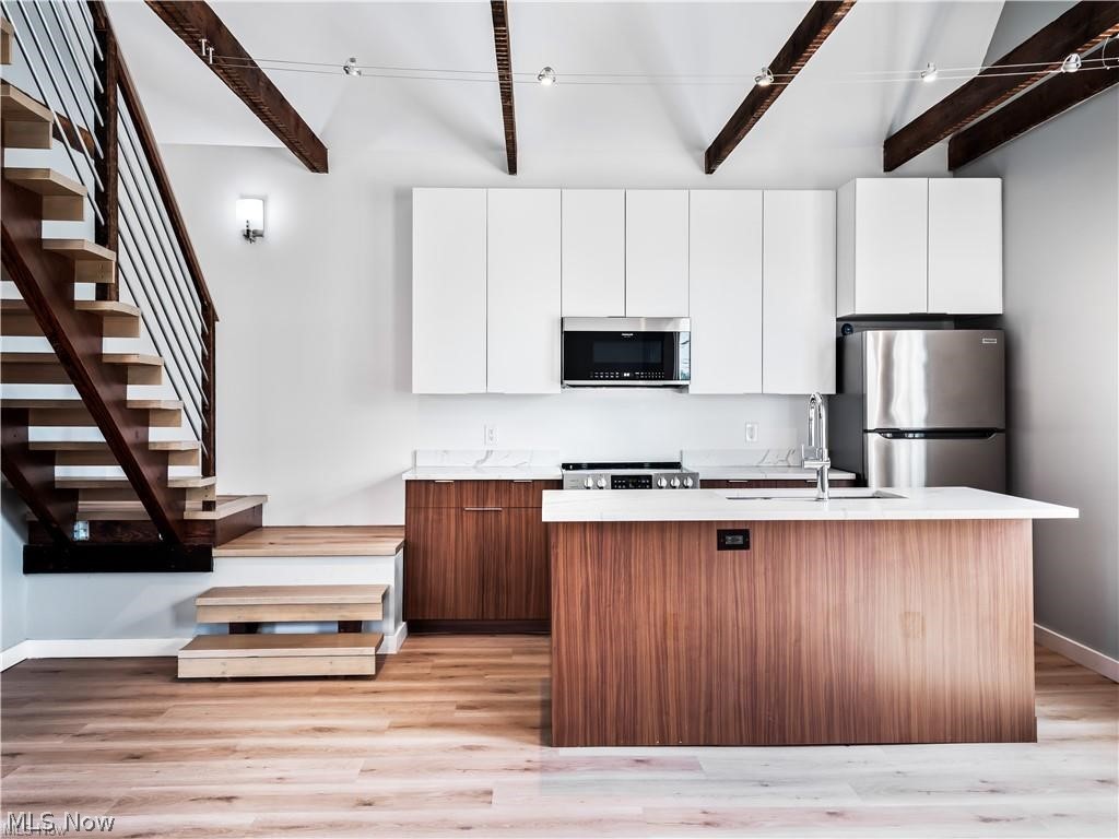 2401 Scranton Road, Unit A Cleveland, OH 44113 - Photo 3 of 17 Modern kitchen with white cabinetry, quartz countertops, and wood-finish lower cabinets and island