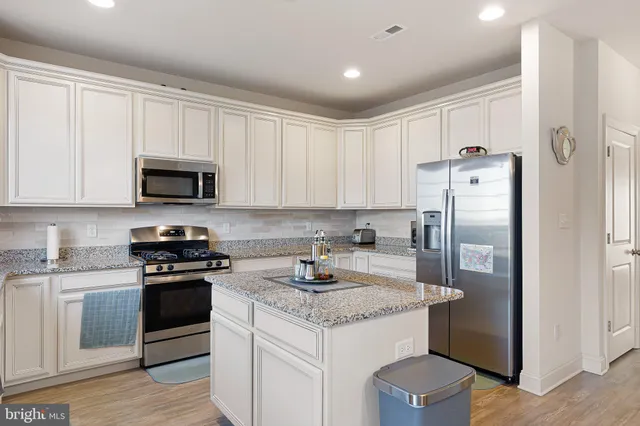 a kitchen with stainless steel appliances granite countertop a refrigerator stove and white cabinets