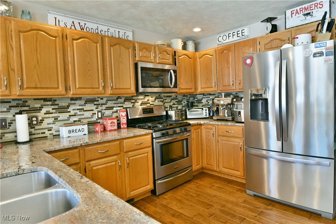 5915 Downs Road Northwest Warren, OH 44481 - Photo 9 of 50 Kitchen with appliances with stainless steel finishes, light stone countertops, a textured ceiling, and backsplash