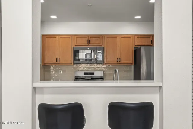 a kitchen with stainless steel appliances granite countertop a refrigerator a stove a sink and a microwave