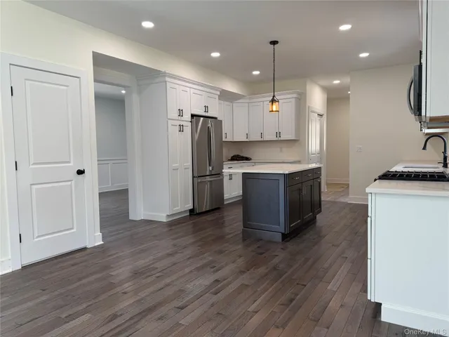 a kitchen with stainless steel appliances granite countertop a refrigerator a sink dishwasher a stove and a refrigerator with wooden floor