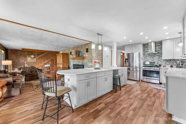a kitchen with kitchen island granite countertop a stove and a view of living room