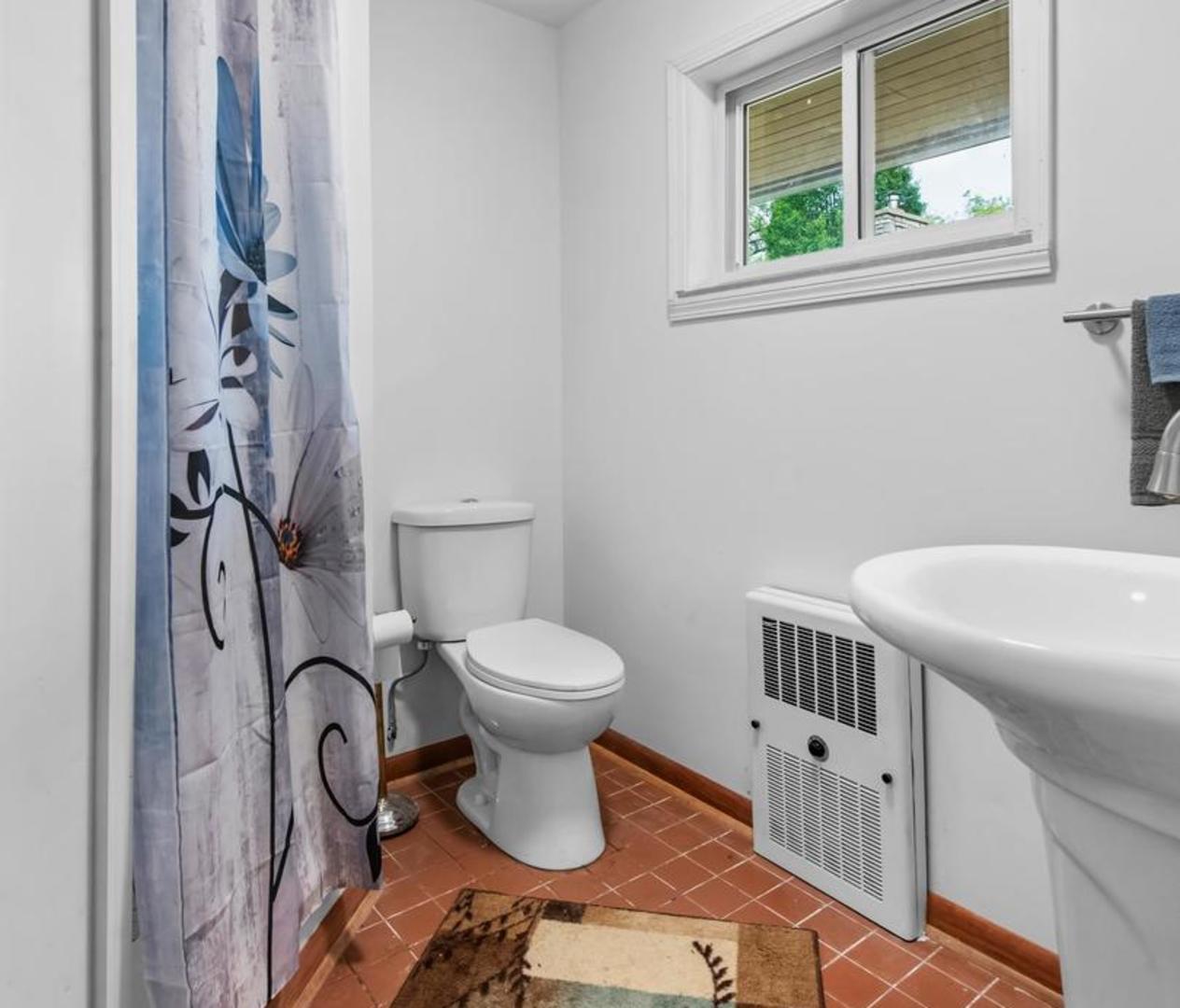 1423 North River Road McHenry, IL 60051 - Photo 22 of 49 a bathroom with a toilet a sink and a window