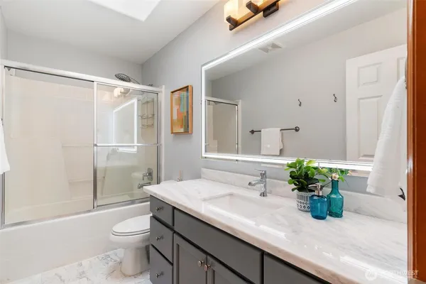 a bathroom with a granite countertop sink a toilet and shower