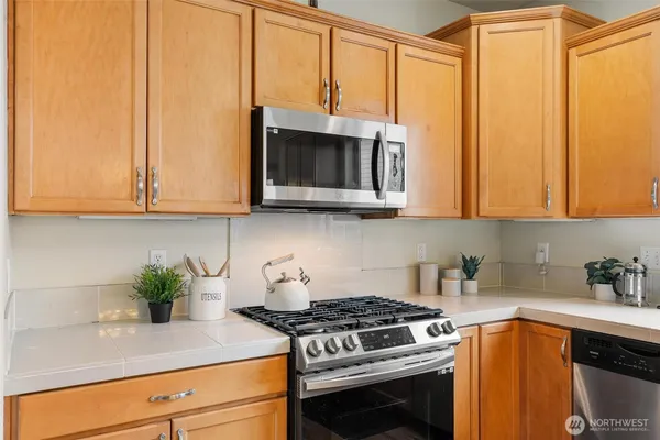 a kitchen with stainless steel appliances granite countertop white cabinets and a stove top oven