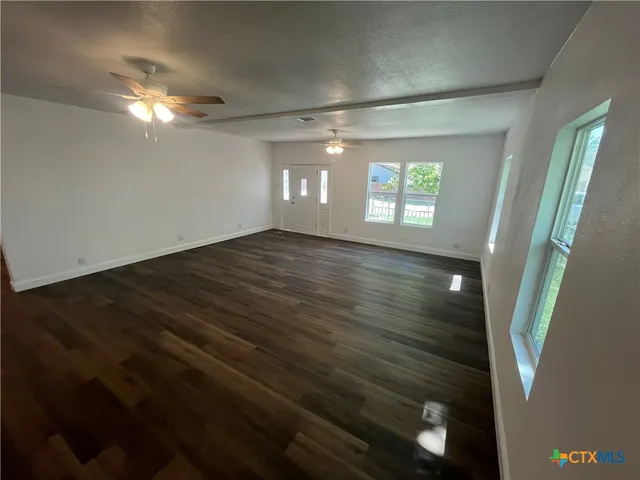 en empty room with window and hardwood floor
