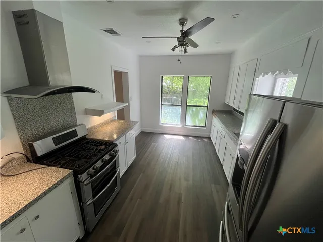 a kitchen with stainless steel appliances granite countertop a stove a refrigerator a sink dishwasher and wooden floor