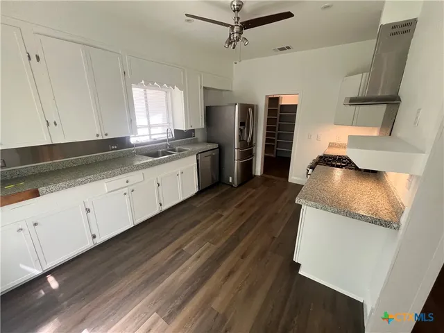 a kitchen with granite countertop a sink a stove and refrigerator