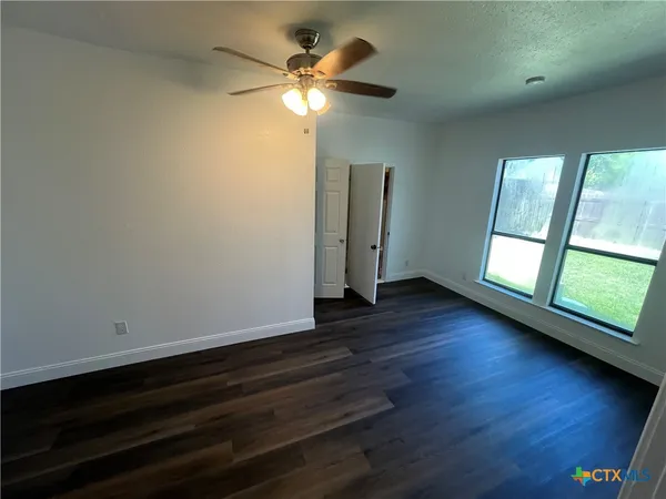 an empty room with wooden floor and windows