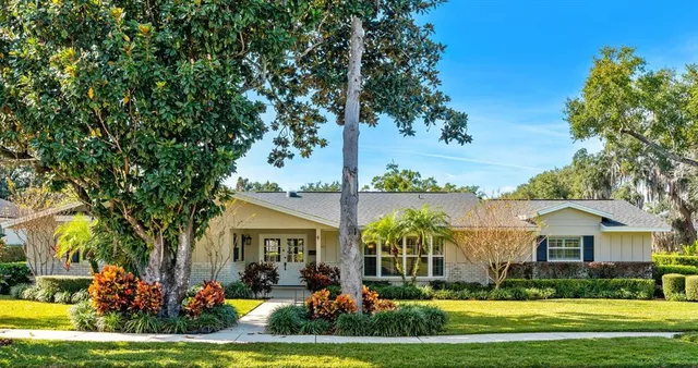 a front view of a house with a garden and trees