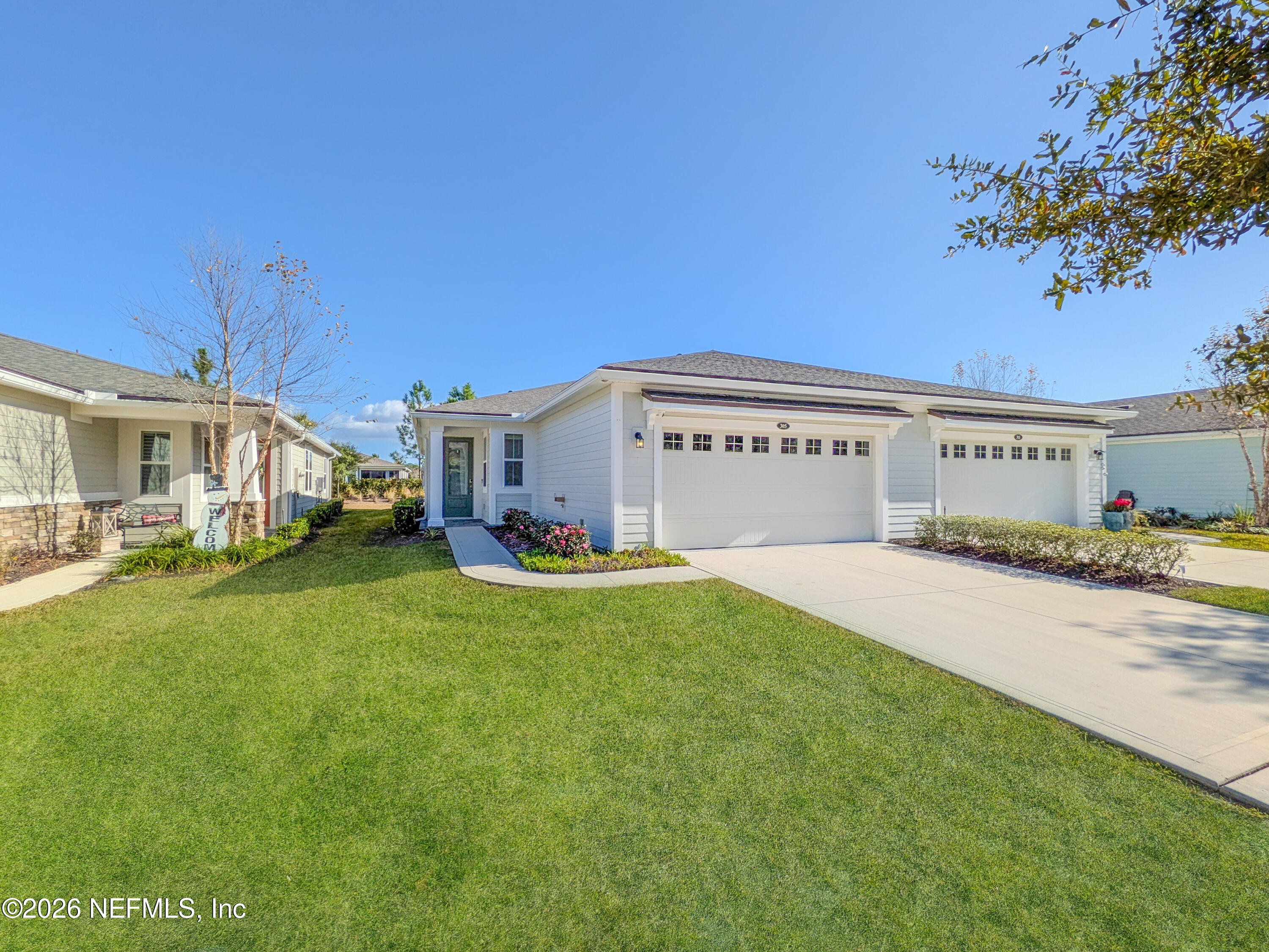 a view of a white house with a big yard and large tree