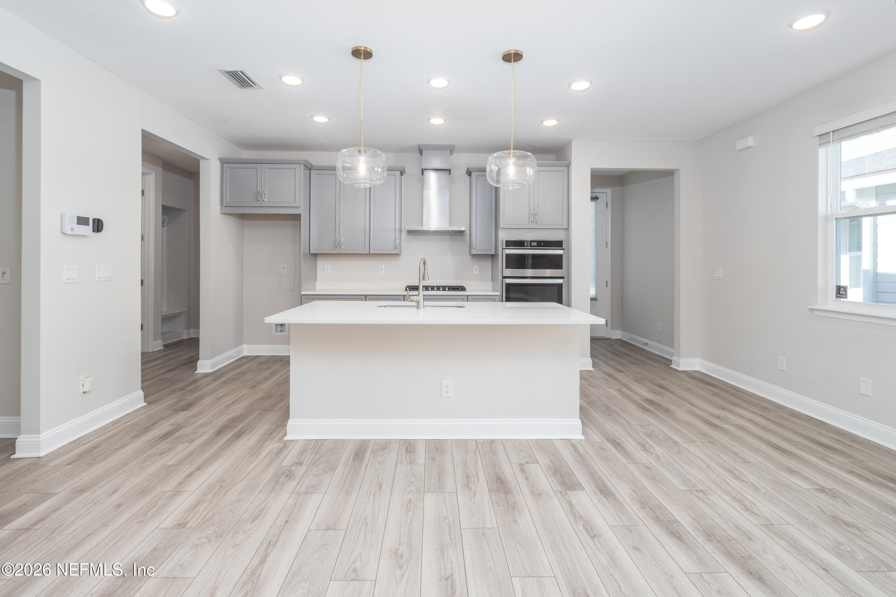 305 Kellet Way St. Johns, FL 32259 - Photo 9 of 42 a large white kitchen with kitchen island a sink wooden floor and a refrigerator in it