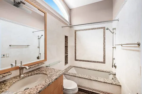 a bathroom with a granite countertop sink mirror vanity and toilet