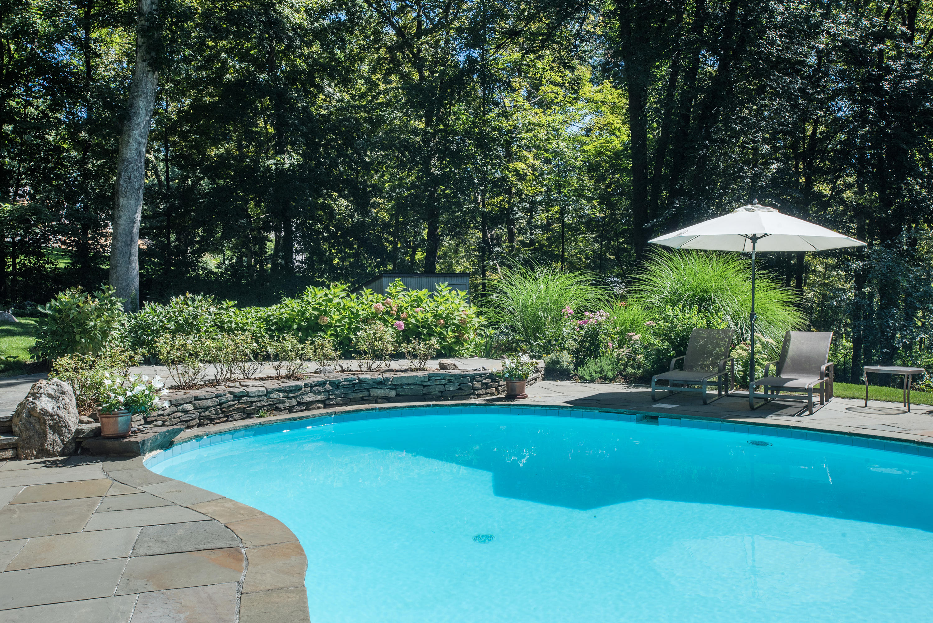 46 Chalburn Road Redding, CT 06896 - Photo 29 of 39 a view of a backyard with plants and a table and chairs under an umbrella