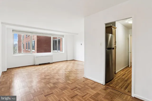 a view of an empty room with window and wooden floor