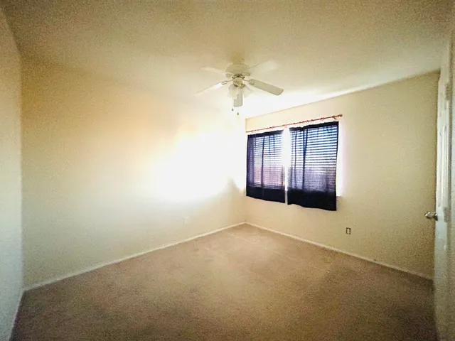 an empty room with a ceiling fan and a window