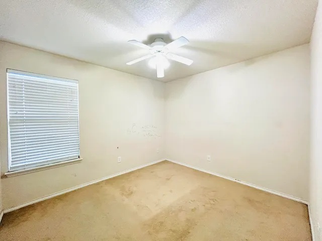 an empty room with a window and a ceiling fan