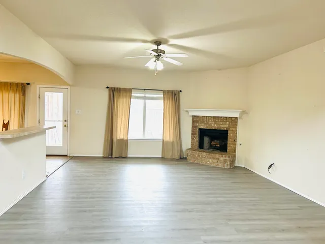 an empty room with wooden floor a fireplace and windows