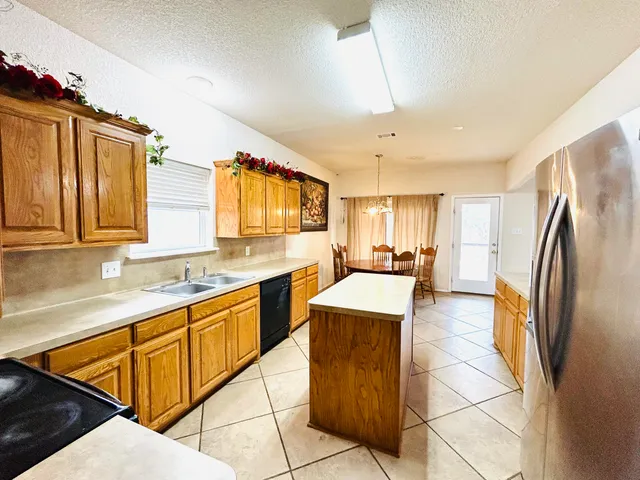 a kitchen with stainless steel appliances granite countertop a refrigerator a sink dishwasher a stove with wooden cabinets and floor